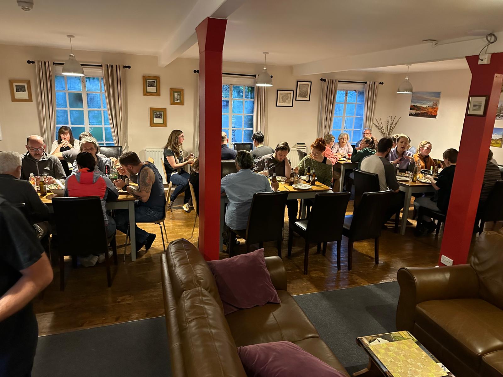 Group of friends and family sharing a meal in the Elterwater hostel dining room.